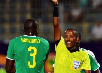 Ethiopian referee Bamlak Tessema Weyesa shows a yellow card to Senegal's defender Kalidou Koulibaly (L) during the 2019 Africa Cup of Nations (CAN) Semi-final football match between Senegal and Tunisia at the 30 June stadium in Cairo on July 14, 2019. (Photo by Giuseppe CACACE / AFP)
