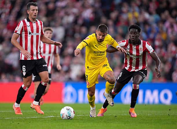 Liga - Girona de Papa Dame Ba tient en échec l'Atletic Bilbao de Boiro (1-1) - wiwsport BILBAO, SPAIN - SEPTEMBER 23: Portu of Girona and Adama Boiro of Athletic Club compete for the ball during the LaLiga EA Sports match between Athletic Club and Girona FC at Estadio de San Mames on September 23, 2025 in Bilbao, Spain. (Photo by Juan Manuel Serrano Arce/Getty Images)